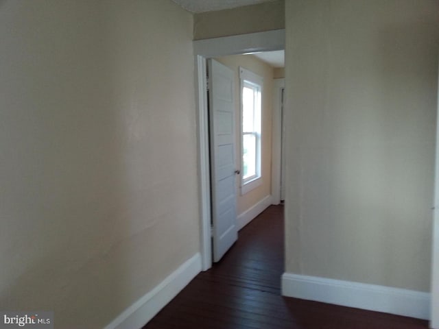 hallway featuring baseboards and dark wood finished floors