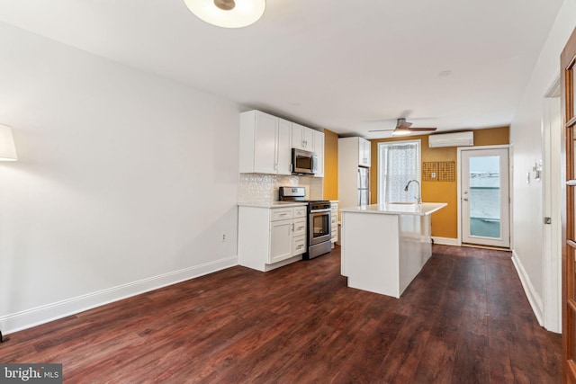 kitchen with appliances with stainless steel finishes, white cabinetry, decorative backsplash, a center island with sink, and a wall unit AC