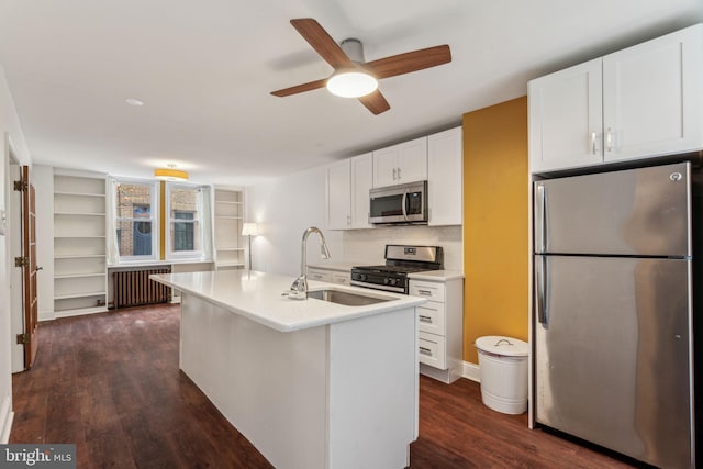 kitchen with sink, a center island with sink, appliances with stainless steel finishes, radiator heating unit, and white cabinets