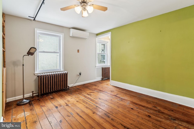 empty room with a wall mounted AC, radiator, and hardwood / wood-style floors