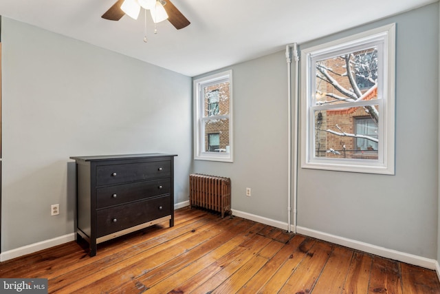 bedroom featuring hardwood / wood-style floors, radiator heating unit, and ceiling fan