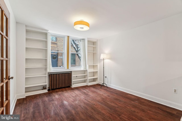 spare room with dark wood-type flooring and radiator heating unit