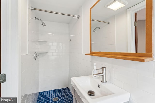 bathroom featuring tile walls, sink, and tiled shower