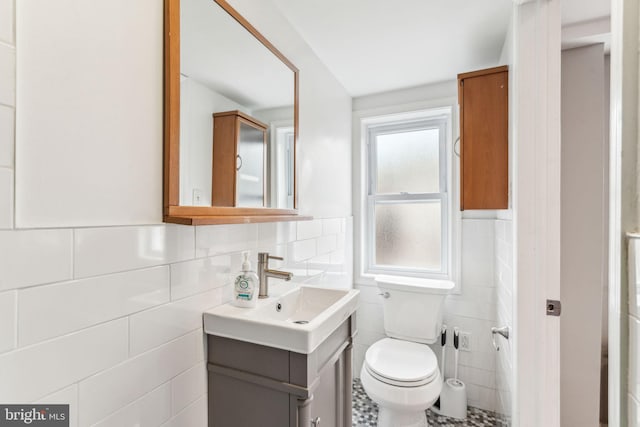 bathroom with vanity, toilet, and tile walls