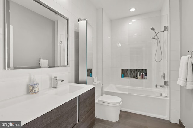 full bathroom featuring tiled shower / bath, vanity, and toilet