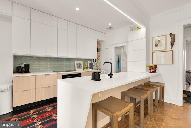 kitchen with light countertops, backsplash, a breakfast bar area, and modern cabinets