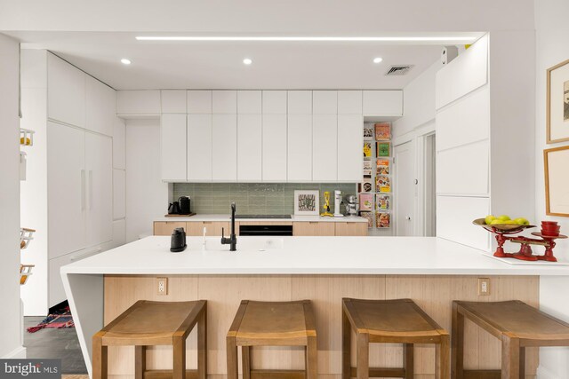 kitchen featuring modern cabinets, white cabinetry, light countertops, and a kitchen breakfast bar