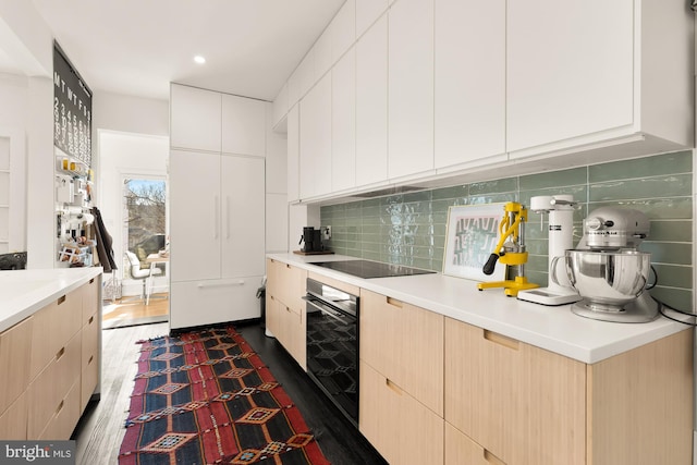 kitchen with light brown cabinets, light countertops, backsplash, and black appliances