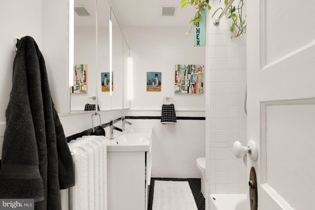 full bath featuring tile walls, radiator, visible vents, toilet, and vanity