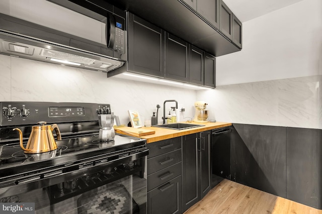 kitchen featuring black appliances, dark cabinets, wooden counters, and a sink