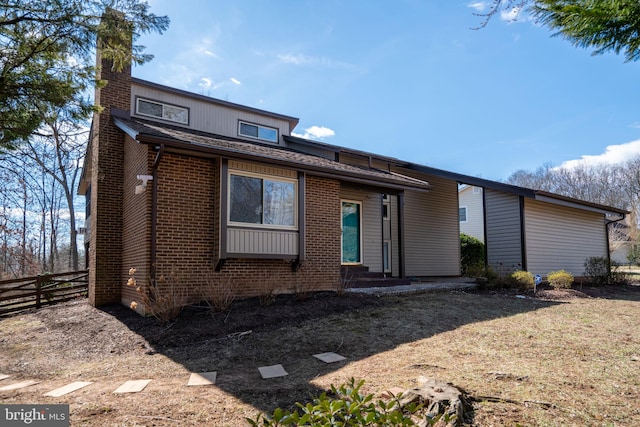 view of front of house featuring a chimney, fence, and brick siding