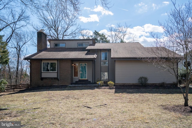 view of front facade with brick siding, fence, roof with shingles, a chimney, and a front yard