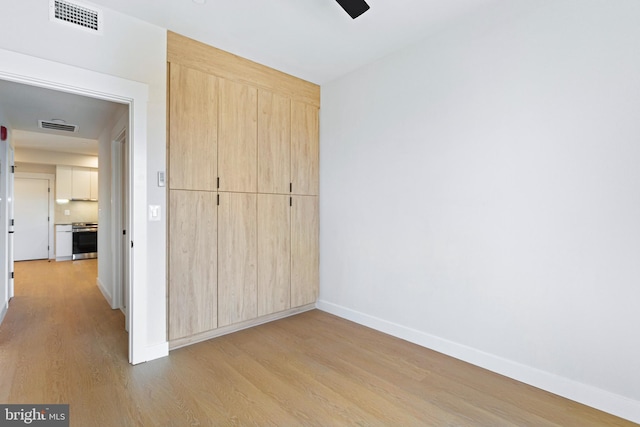 unfurnished bedroom with ceiling fan, light wood-type flooring, and a closet