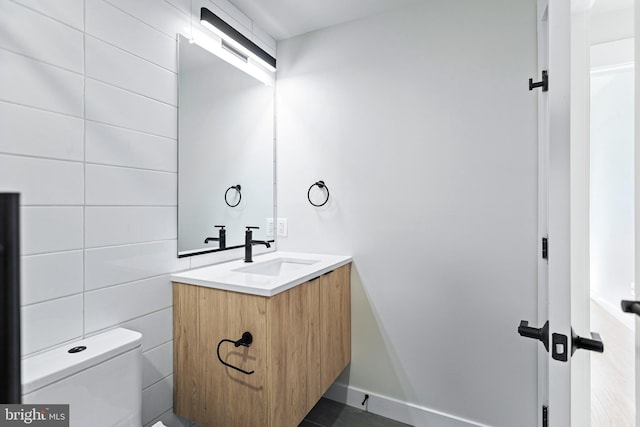 bathroom featuring vanity, tile walls, and toilet