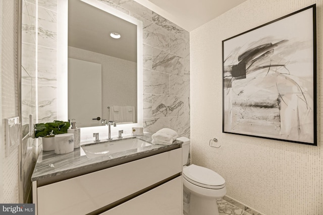 bathroom with vanity, tile walls, and toilet