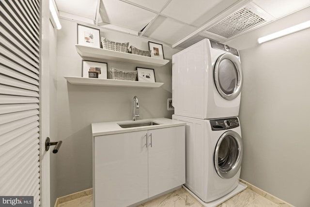 clothes washing area featuring sink, cabinets, and stacked washing maching and dryer