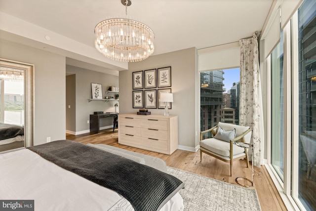 bedroom with multiple windows, an inviting chandelier, and light wood-type flooring