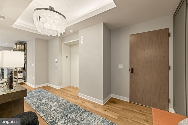 hall featuring a tray ceiling and light hardwood / wood-style flooring