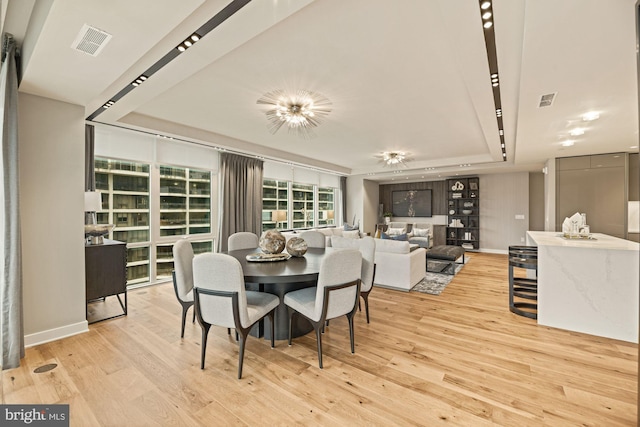 dining room featuring a tray ceiling and light hardwood / wood-style flooring