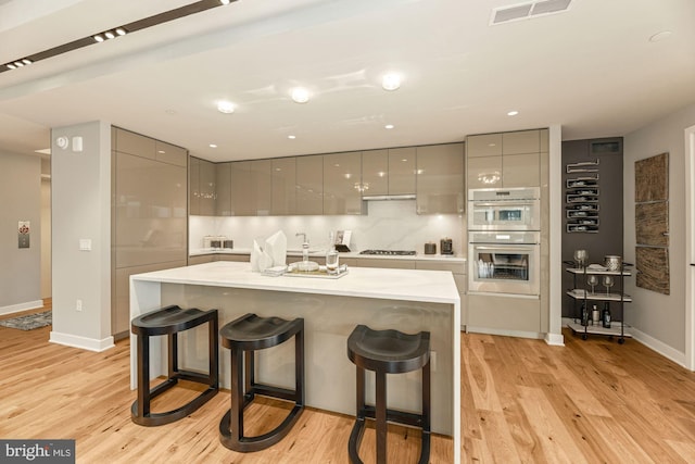 kitchen with appliances with stainless steel finishes, a kitchen breakfast bar, and gray cabinets