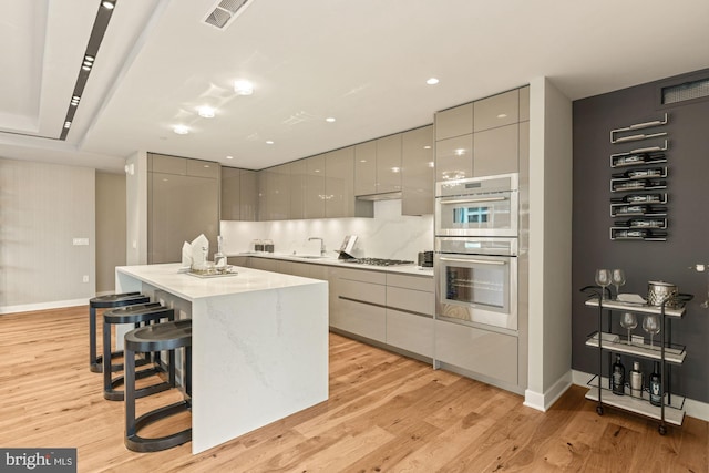 kitchen featuring appliances with stainless steel finishes, a kitchen breakfast bar, gray cabinets, and a kitchen island