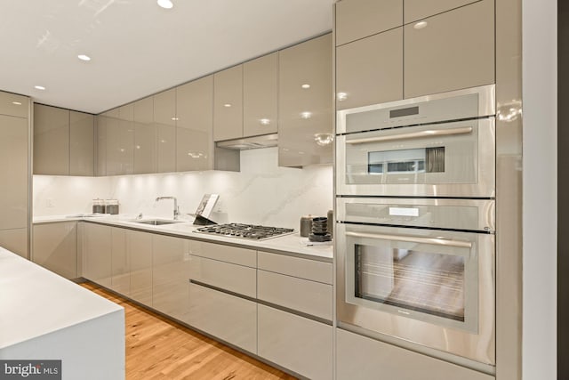 kitchen featuring sink, gray cabinets, backsplash, stainless steel appliances, and light hardwood / wood-style floors