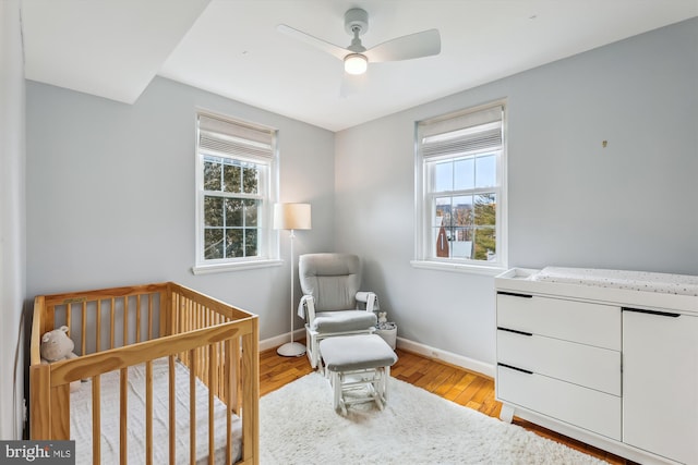 bedroom featuring a crib, multiple windows, and light wood-type flooring