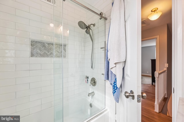 bathroom featuring hardwood / wood-style flooring and combined bath / shower with glass door