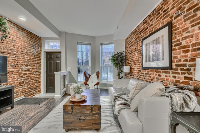 living room with brick wall and dark hardwood / wood-style floors