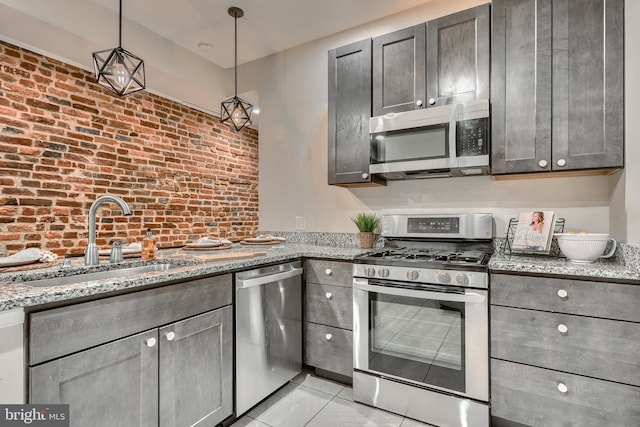 kitchen featuring light tile patterned flooring, appliances with stainless steel finishes, pendant lighting, sink, and light stone countertops