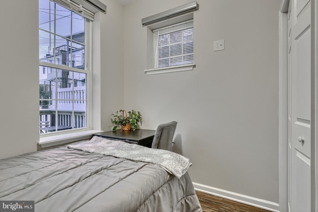 bedroom with dark hardwood / wood-style floors and multiple windows