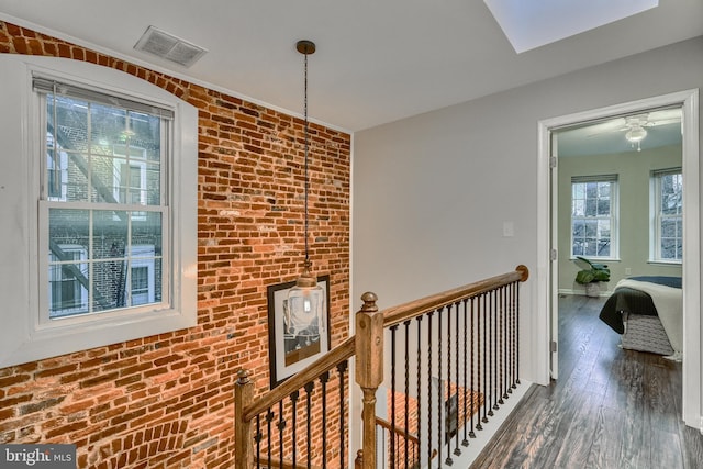 hallway featuring brick wall and dark hardwood / wood-style floors