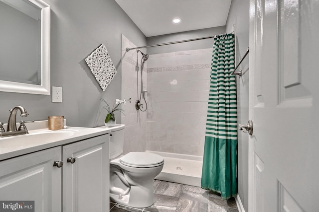 bathroom with walk in shower, vanity, and toilet