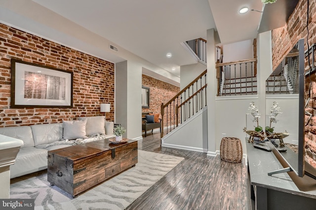 living room with brick wall and dark hardwood / wood-style floors