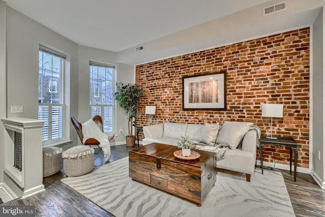 living room with brick wall and dark hardwood / wood-style floors