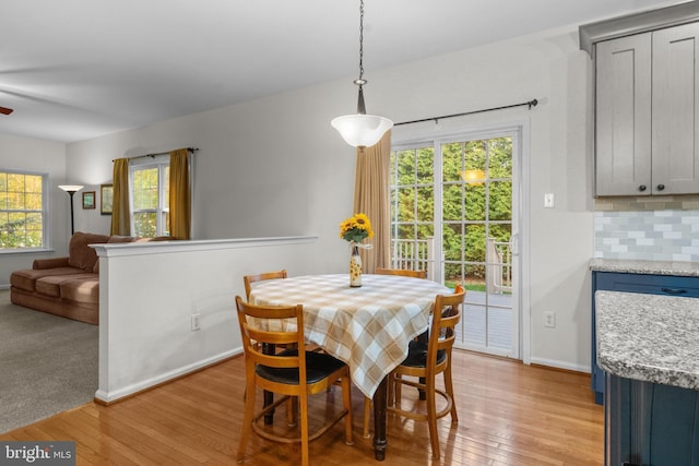 dining room with a healthy amount of sunlight, baseboards, ceiling fan, and light wood finished floors