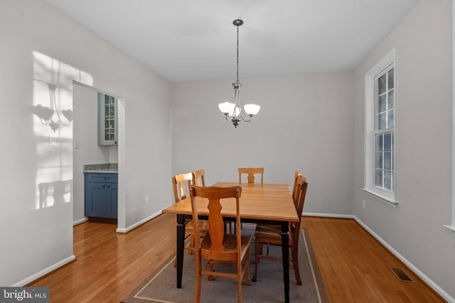 dining space featuring visible vents, light wood-style flooring, baseboards, and a chandelier