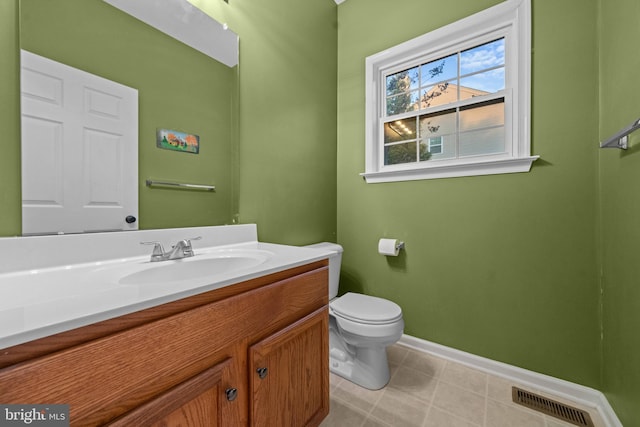 half bath with visible vents, tile patterned flooring, baseboards, vanity, and toilet