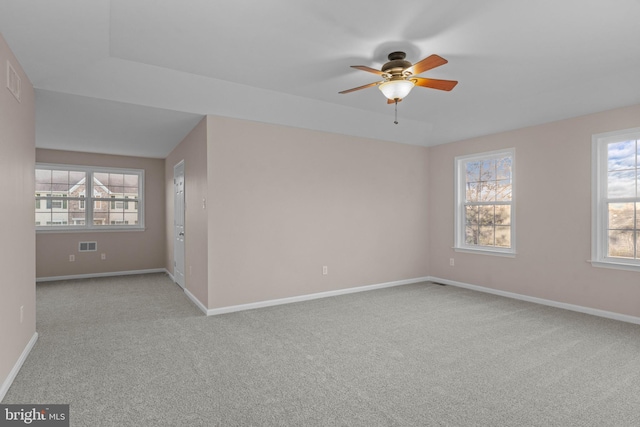 carpeted spare room with baseboards, ceiling fan, and visible vents