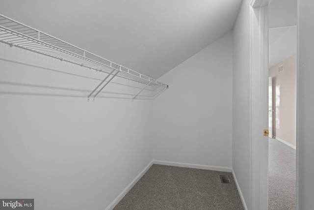 spacious closet featuring visible vents, carpet, and lofted ceiling
