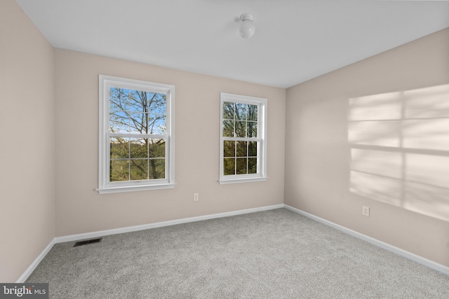 carpeted empty room featuring baseboards and visible vents