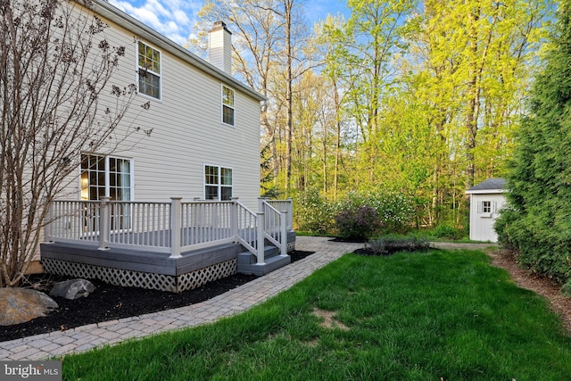 back of property featuring a chimney, a lawn, a deck, an outbuilding, and a storage unit