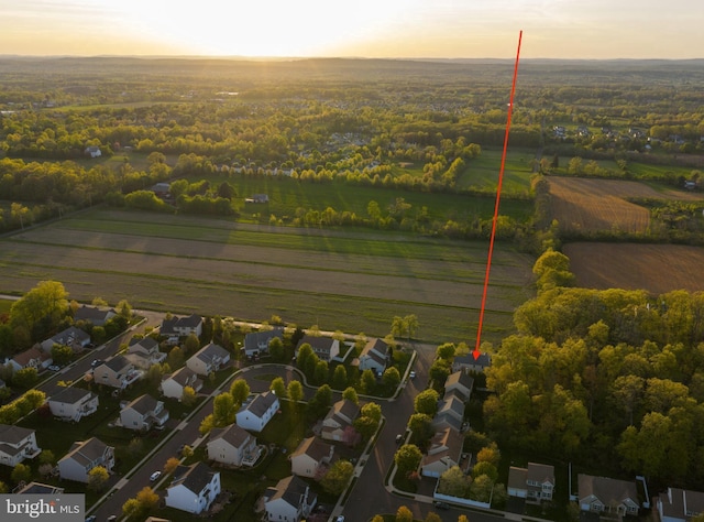 aerial view at dusk featuring a rural view and a residential view