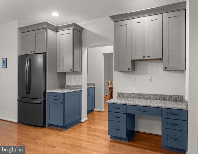 kitchen featuring built in desk, light wood finished floors, freestanding refrigerator, recessed lighting, and baseboards
