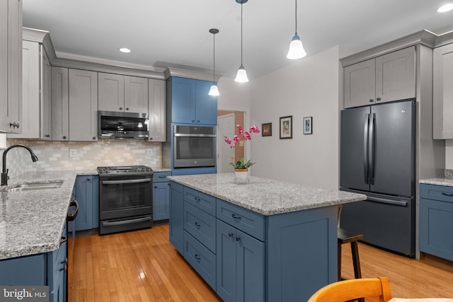 kitchen with stainless steel appliances, tasteful backsplash, a sink, light wood-style flooring, and blue cabinetry