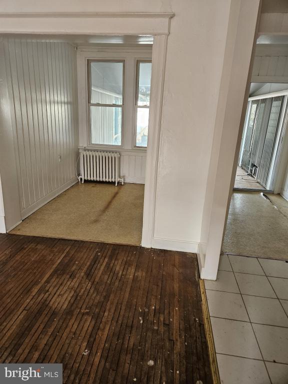 empty room with a wealth of natural light, radiator heating unit, and wood-type flooring