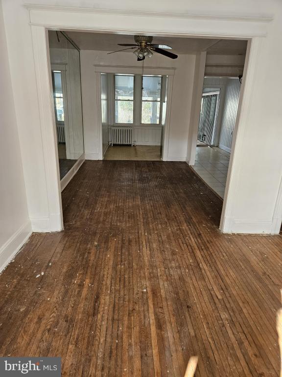 empty room featuring ceiling fan, radiator, and dark hardwood / wood-style flooring