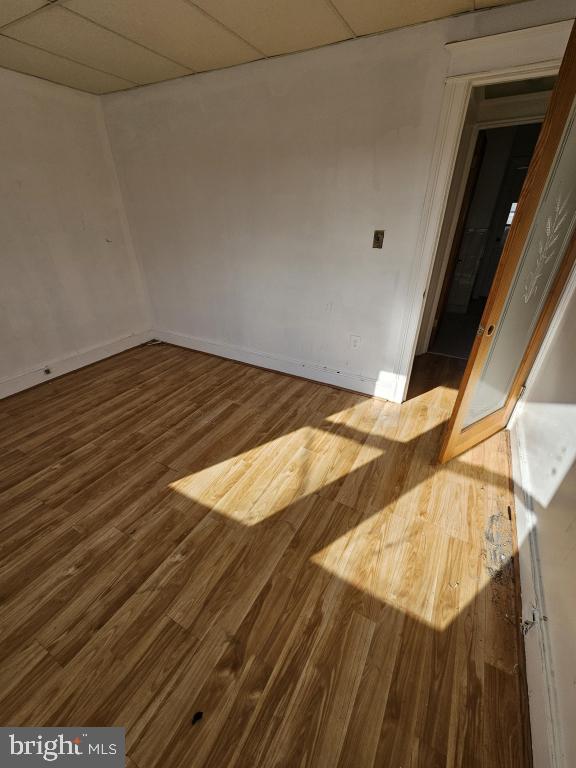 unfurnished room featuring hardwood / wood-style flooring and a drop ceiling