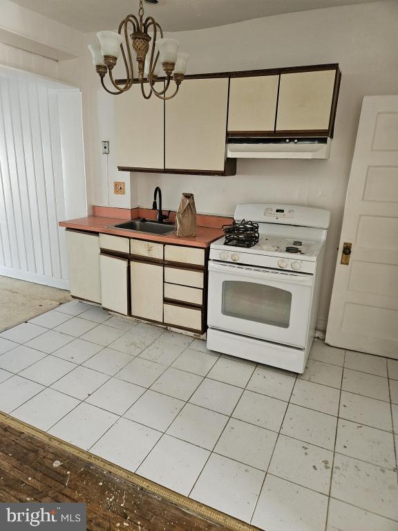 kitchen with white cabinetry, sink, white appliances, and a notable chandelier