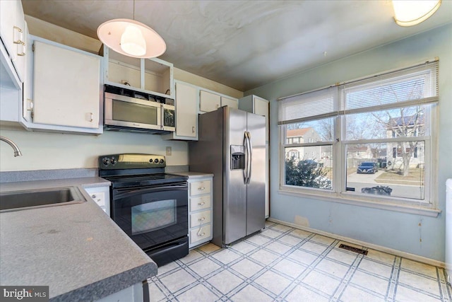 kitchen featuring sink, appliances with stainless steel finishes, white cabinetry, and decorative light fixtures